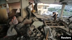 A Palestinian woman, left, cries inside her damaged house, which police said was targeted in an Israeli airstrike in Gaza City, July 17, 2014. 