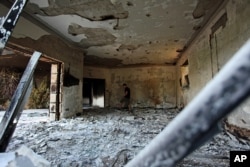 FILE - A Libyan man walks in the damaged U.S. consulate after an attack the night of Sept. 11, 2012, in Benghazi, Libya.