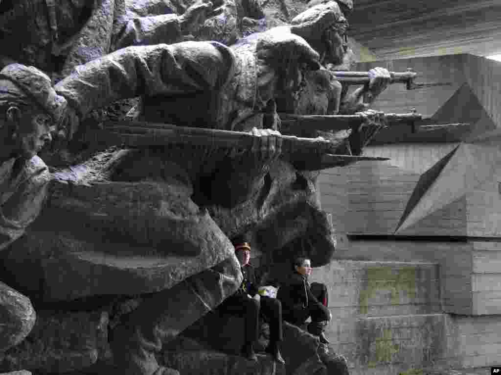 Military cadets rest on part of the WWII memorial sculpture as they prepare for a parade of military schools&nbsp; to celebrate Victory Day in Kyiv, Ukraine. Ukraine marks Victory Day on May 9.