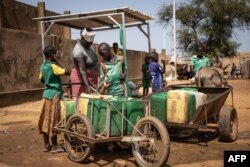 Les enfants remplissent leur bidon d'eau à la pompe à eau, dans un site qui accueille des personnes déplacées internes à Kaya, le 14 octobre 2020.