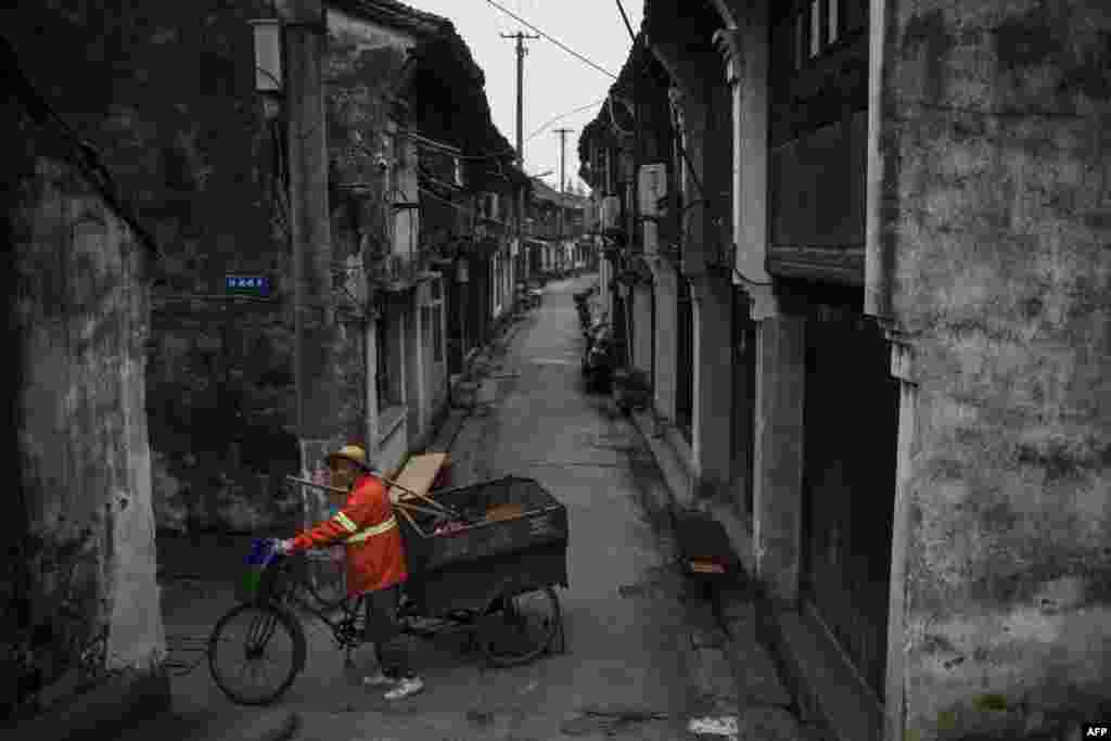 A street cleaner pushes his tricycle through the alleys of Wuzhen Township of Tongxiang City, in east China's Zhejiang province.