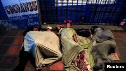 FILE - People sleep on makeshift beds on a street, where Venezuelan migrants gather to spend the night, in Maicao, Colombia, Feb. 15, 2018. 