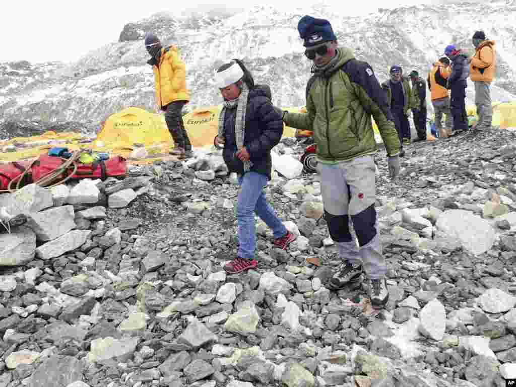 In this photo provided by Azim Afif, a man helps an injured woman after she is checked by a doctor at the International Mount Guide (IMG) camp at Everest Base Camp, Nepal, April 26, 2015.