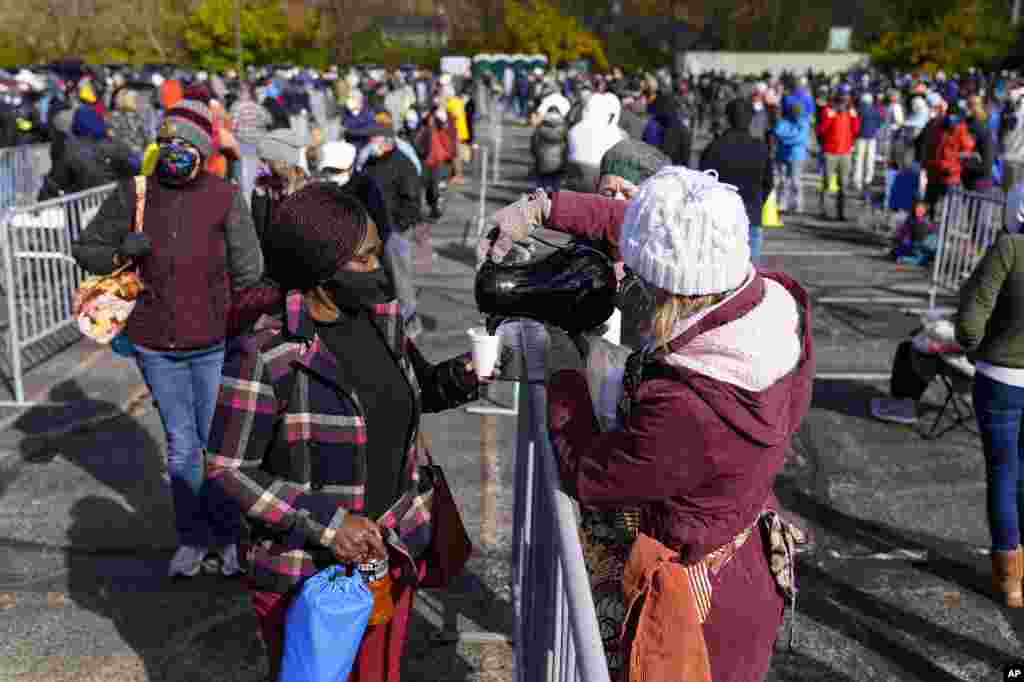 Volunteers distribute coffee as voters wait in long lines to cast their ballots during early voting at St. Luke's United Methodist Church in in Indianapolis, Friday, Oct. 30, 2020. The wait to vote at this location is expected to be over 5 hours. (AP Phot