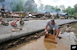 Mark Lester cleans out a box with creek water as he cleans up from severe flooding in White Sulphur Springs, W. Va., June 24, 2016.