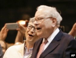 Berkshire Hathaway Chairman and CEO Warren Buffett and Berkshire Director Bill Gates (left) react to a successful throw during a newspaper tossing competition at the annual Berkshire Hathaway shareholders meeting at the CenturyLink Center in Omaha, Neb.