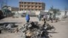 Des passants sur le site bombardé à Mogadiscio près du minitère du travail, le 23 mars 2019. 