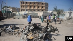 Des passants sur le site bombardé à Mogadiscio près du minitère du travail, le 23 mars 2019. 