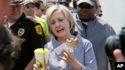 Hillary Clinton comiendo una costilla de cerdo y tomando limonada durante su visita a la Feria Estatal de Iowa, en Des Moines, el sábado, 15 de agosto de 2015.