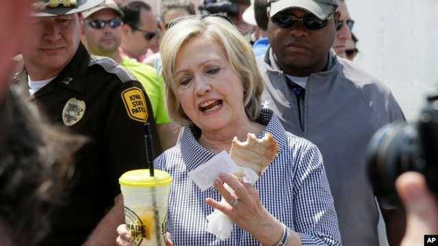 Hillary Clinton comiendo una costilla de cerdo y tomando limonada durante su visita a la Feria Estatal de Iowa, en Des Moines, el sábado, 15 de agosto de 2015.