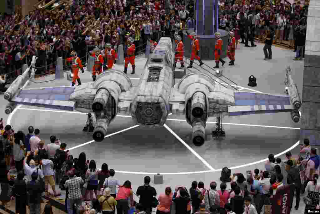 People are greeted by "x-wing pilots" as they gather around a life-sized Star Wars X-wing Fighter model on display at Singapore's Changi Airport.