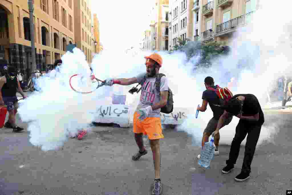 An anti-government protester uses a a tennis racket to hit back a tear gas canister at riot police during a protest following last Tuesday&#39;s massive explosion which devastated Beirut, Lebanon.