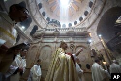 Latin Patriarch of Jerusalem Pierbattista Pizzaballa, center, walks with Christian clergymen holding candles during the Easter Sunday procession at the Church of the Holy Sepulchre in Jerusalem, April 16, 2017.