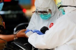 Petugas kesehatan yang mengenakan alat pelindung mengambil sampel darah untuk menguji seorang pria terhadap virus corona (COVID-19) di Bogor, Jawa Barat, 7 April 2020. (Foto: Reuters/Willy Kurniawan)