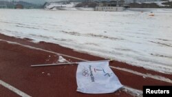 FILE - A flag bearing the logo of 2018 Winter Olympic Games lies on the ground at the proposed site of the Olympic Stadium near the Alpensia Resort in the mountain cluster of PyeongChang.