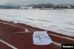 A flag bearing the logo of 2018 Winter Olympic Games lies on the ground at the proposed site of the Olympic Stadium near the Alpensia Resort in the mountain cluster of PyeongChang, February 10, 2015.