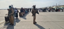کابل ایئرپورٹ پر طیارے میں سوار ہونے کے لیے لوگ قطار میں کھڑے ہیں۔ 21 اگست 2021