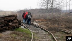 Des migrants marchent sur des voies ferrées près de la ville de Sid, à l'ouest de la Serbie, près de la frontière serbe avec un membre de l'Union européenne, la Croatie, le 18 décembre 2017.