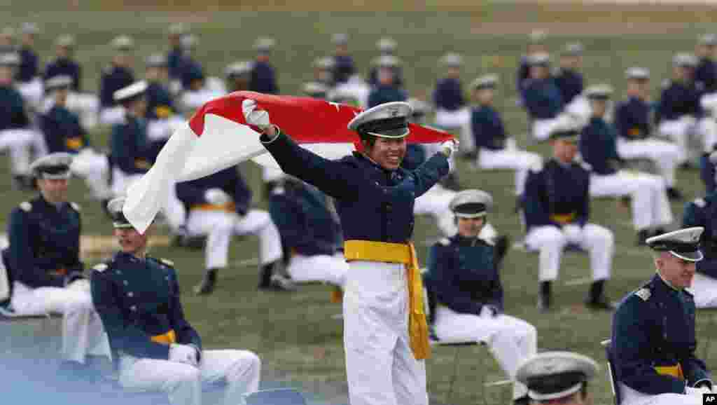 Christabel Chai, de Singapur, despliega la bandera de su tierra natal mientras es honrada con otros cadetes nacidos en el extranjero, durante la ceremonia de graduación de los cadetes de la Fuerza Aérea de EE.UU.