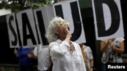 A woman shouts slogans during a protest outside the World Health Organization (WHO) office in Caracas, Venezuela, Sept. 25, 2017. The letters read "Health."