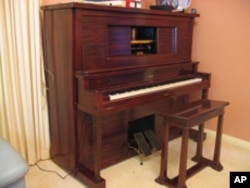 This is a player piano, also called a pianola. The piano roll, inserted into the opening, can play a tune, or the instrument can be played like a normal piano.