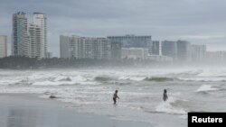 Las personas entran en una playa mientras el huracán Rick se acerca a la costa mexicana al norte de Acapulco, México, 24 de octubre de 2021.