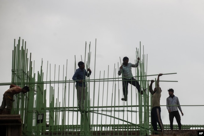 Laborers work at a building site in Mumbai, India, in late November, 2021.