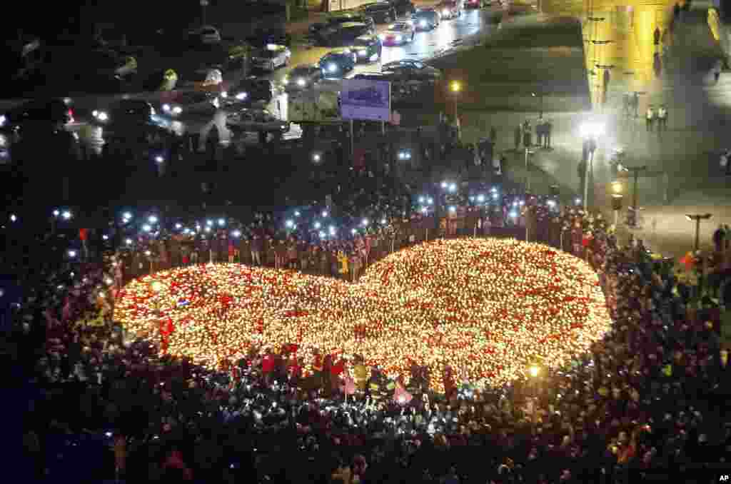 People stand by a heart shaped with candles as a tribute to slain Mayor of Gdansk Pawel Adamowicz in Gdansk, Poland, Jan. 16, 2019.