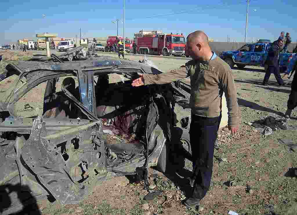 Seorang pria menunjuk sebuah mobil yang hancur akibat pemboman di Kirkuk, sebelah utara Baghdad (AP).
