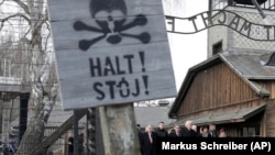 Germany's President Frank-Walter Steinmeier, center, and his wife Elke Buedenbender enter the Auschwitz I Nazi death camp in Oswiecim, Poland, Monday, Jan. 27, 2020.