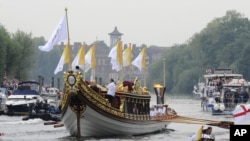 This photo provided by LOCOG shows the royal barge Gloriana carrying Olympic flame burning in the cauldron as it makes its way down the River Thames towards Richmond Bridge during the final day of the Olympic torch relay in London, July 27, 2012. 