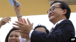 Opposition party leader Sam Raisy, right, claps in front of the National Assembly in Phnom Penh, Cambodia. A Cambodian court has sentenced Rainsy in absentia Wednesday, Jan. 27, 2010, to two years imprisonment for uprooting border markers on the frontier 