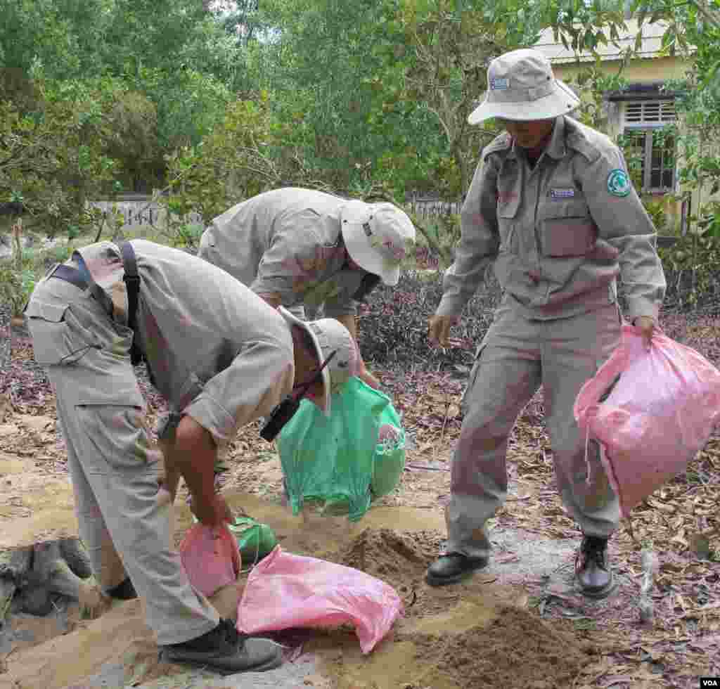 The rapid response team clear up after the explosion, the kindergarten is in the background. (VOA/M. Brown) 