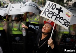 An opposition supporter confronts riot security forces with a sign that reads "No more repression" during a rally against President Nicolas Maduro in Caracas, Venezuela, May 12, 2017.