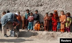 FILE - A child receives polio vaccination drops as others stand in a line during an anti-polio campaign on the outskirts of Jalalabad, Feb. 11, 2013.