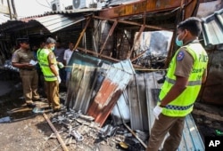 Sri Lankan security officers inspect vandalized shops owned by Muslims in Minuwangoda, a suburb of Colombo, May 14, 2019.