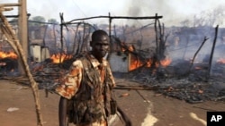 A policeman walks past the smouldering remains of a market in Rubkona near Bentiu in South Sudan, April 23, 2012. 