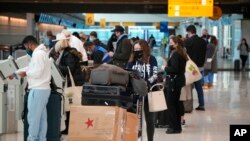 Viajeros esperan en quiosco de American Airlines en el Aeropuerto Internacional de Denver el domingo 26 de diciembre de 2021.
