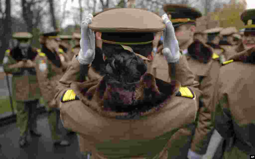 A female member of Romania&#39;s military adjusts her hat before taking part in the national day military parade in Bucharest, Romania.