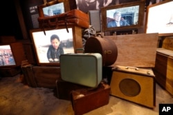 FILE - Luggage, an image of a boy of Japanese descent, and a video interview of a man who was kept in an internment camp, are part of the permanent exhibit "Salute to the Home Front" at the National World War II Museum.