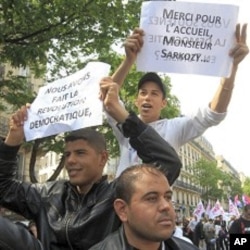 Migrants of North African origin who hold temporary travel documents issued by Italy take part in the the annual May Day march in Paris, May 1, 2011. The posters read " we did the democratic revolution", "thanks for the welcome mister Sarkozy".