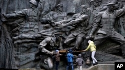 Children play at the monument of the Unknown Soldier, a memorial to World War II veterans, in a memorial park in Kyiv, Ukraine, Nov. 1, 2017.