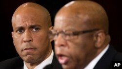 Senator Cory Booker mendengarkan anggota DPR AS John Lewis, keduanya dari Partai Demokrat, dalam kesaksian mereka di Kongres mengenai calon jaksa agung (11/1). (AP/Cliff Owen)