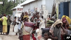 Displaced people carry their belongings as they flee from Badbaado settlement after two groups of Somalia government soldiers clashed inside the camp in the capital Mogadishu, August 5, 2011