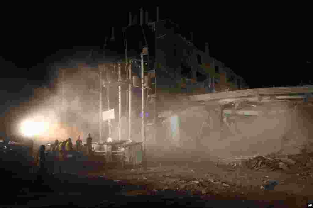 2013年4月29日，在达卡附近的萨瓦镇，消防队员和军人在拆除和清理倒塌的服装厂大楼废墟时，仍然矗立的部分结构坍塌，搜救人员满身灰尘。