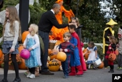President Barack Obama pats a child dressed as Superman on the head during a Halloween event at the White House, 2014.