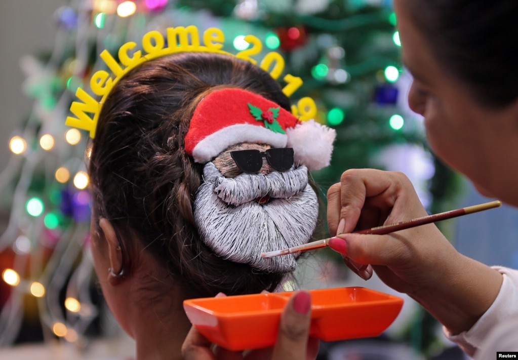 2019년 신년행사에 앞서 인도&nbsp;아마다바드에서 메이크업 아티스트가 여성의 머리를 산타클로스 모습으로 칠하고 있다.&nbsp;
