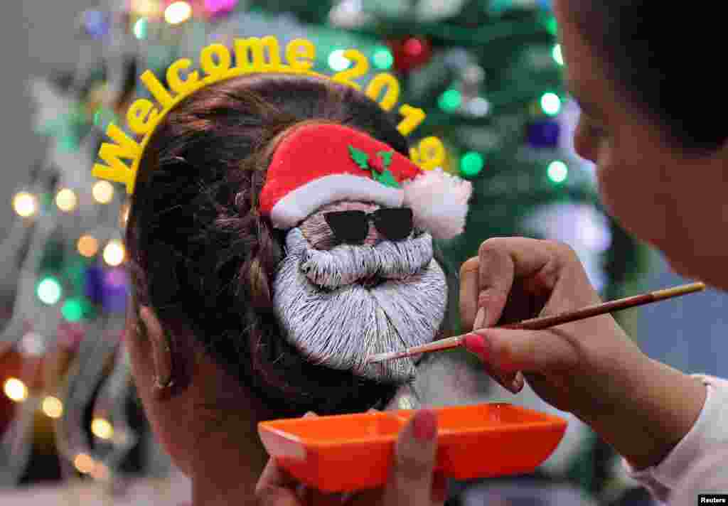 A make-up artist creates a Santa Claus shape in a woman&#39;s hair, during New Year&#39;s preparations in Ahmedabad, India, Dec. 31, 2018.