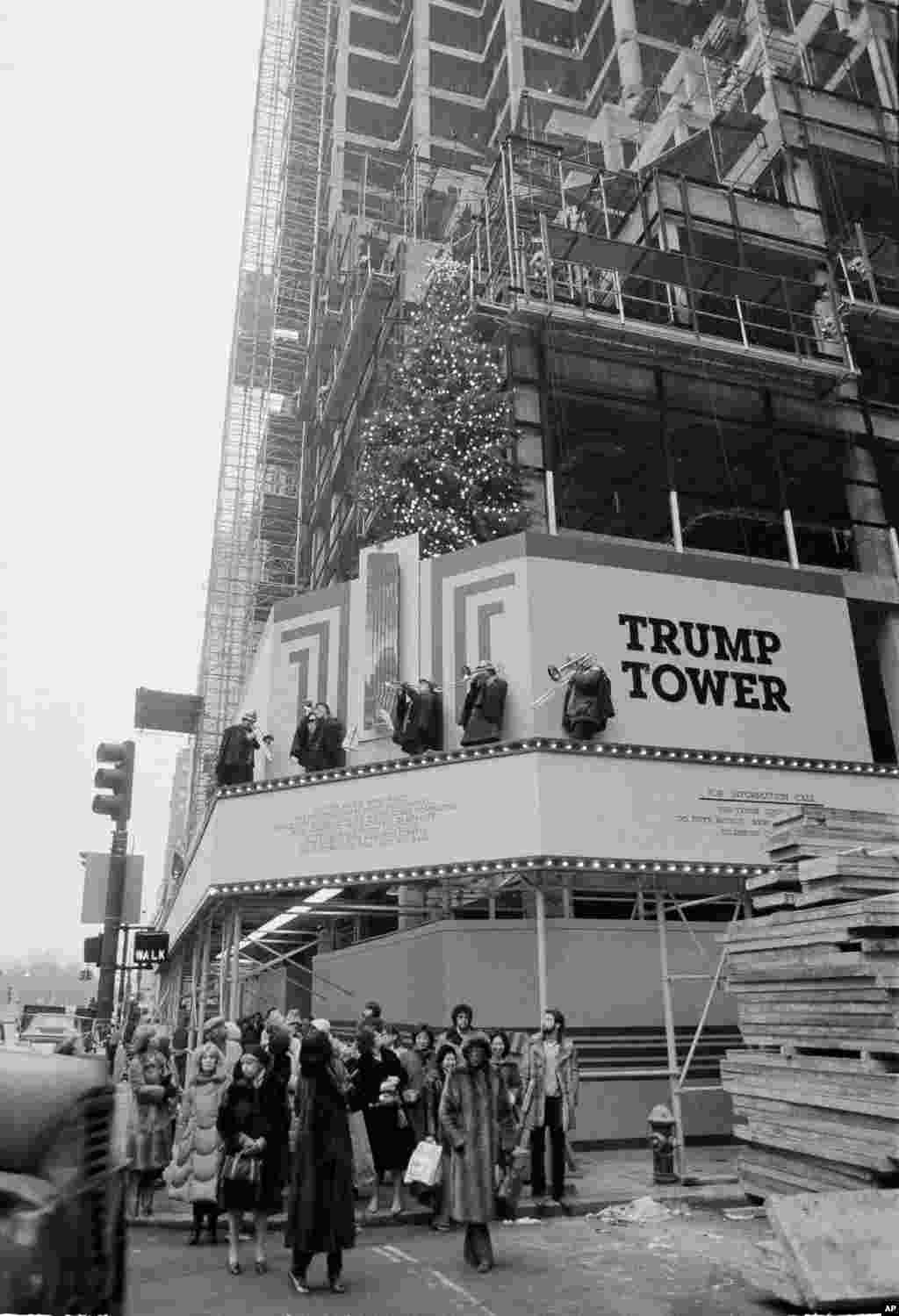 A brass quintet plays atop a ledge above New York's Fifth Avenue on the partially completed Trump Tower, serenading passers-by with Christmas carols as the rush to find last-minute gifts reach a frenzied pace, Dec. 23, 1981. (AP Photo/Suzanne Vlamis)