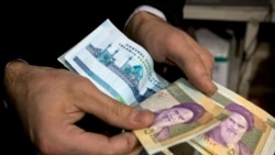 (FILE) A vendor counts money in a shop in Tehran.